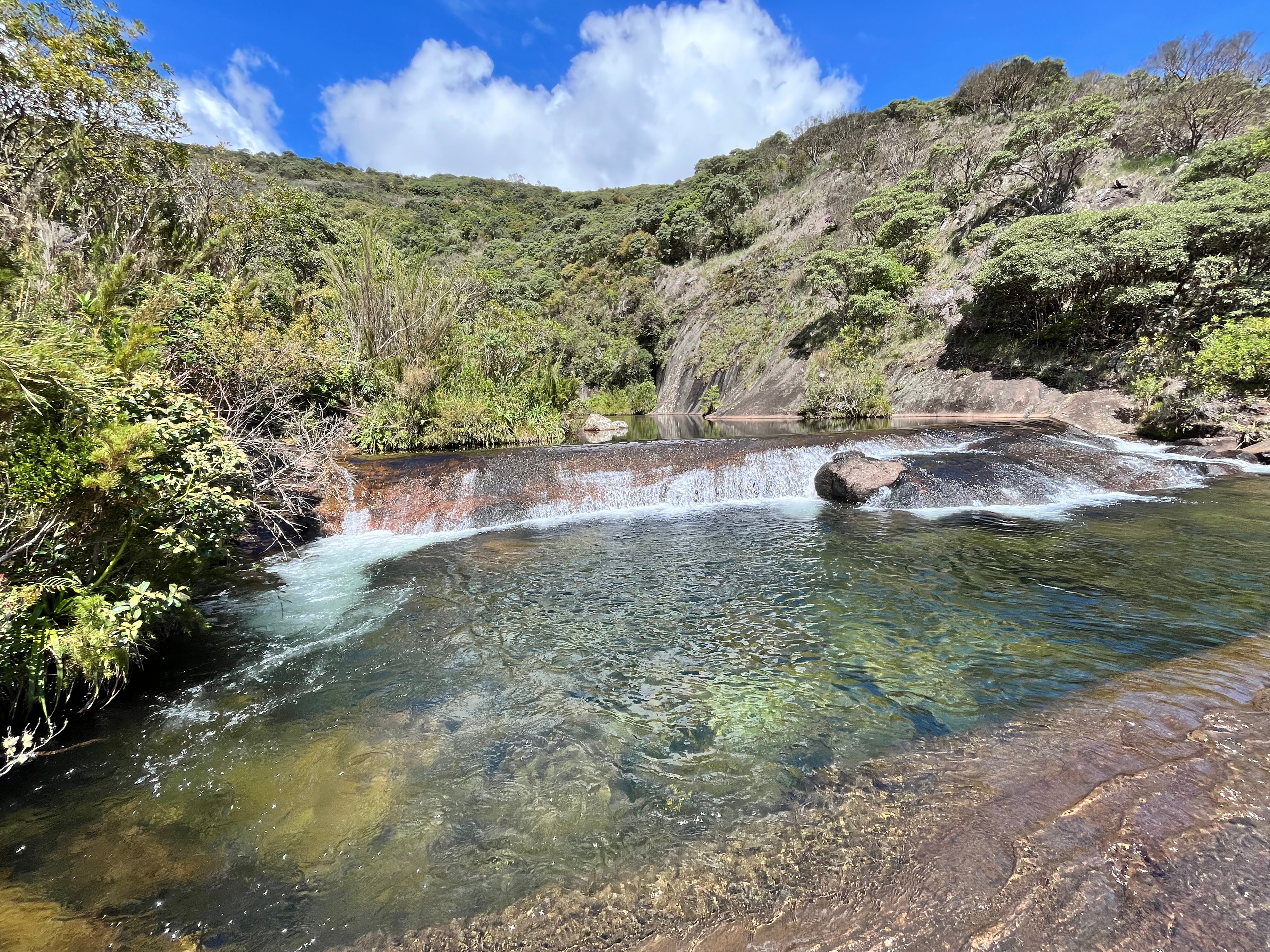 poço de uma pequena cachoeira com vegetação ao fundo, imagem de uma cachoeira no parque nacional do caparaó